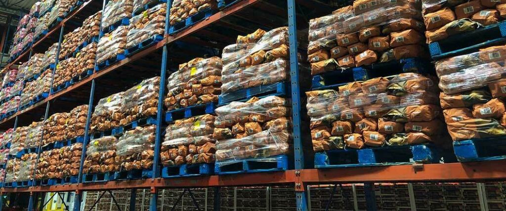 Sacks of potatoes stored on shelves in a warehouse.