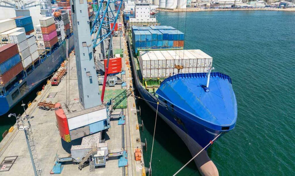 A cargo vessel being loaded with containers prior to leaving its dock.