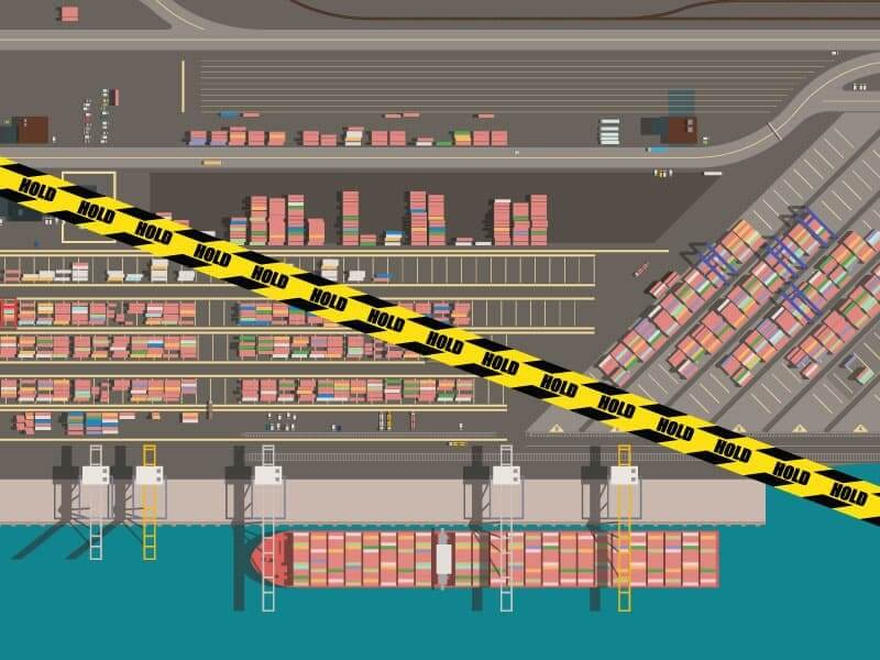 A stylized digital image depicting an overhead view of a container ship docked at a port with cranes, containers, and multiple modes of transportation visible. A strip of black and yellow caution tape labeled “hold” overlaps the image, supporting the article title “CPSC Customs Hold: What it is, How to Resolve, and More”.
