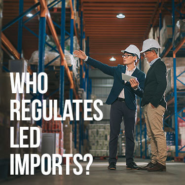 Two business men in hard hats stand in a warehouse as one gestures to the other
