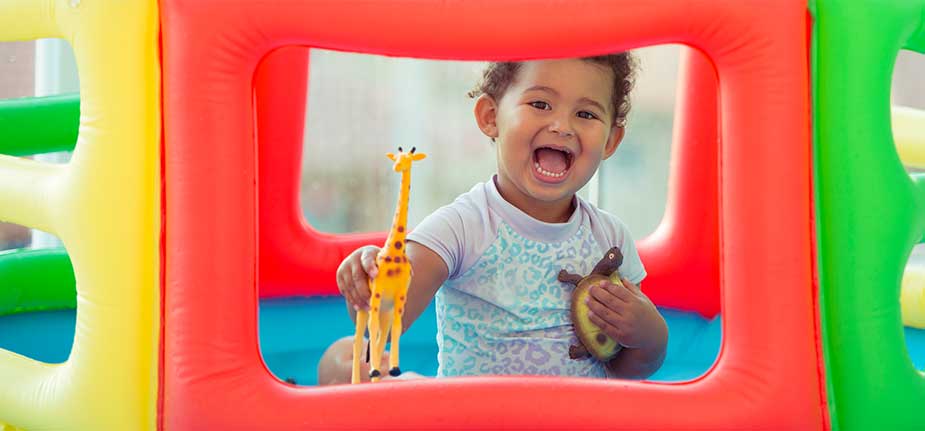 toddler playing with animal toys inside play pen