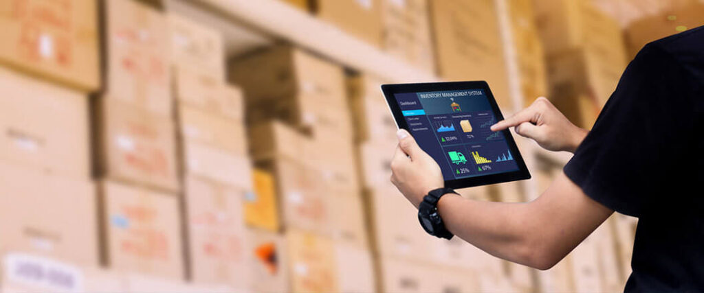 person making calculation on a tablet with boxes stacked in the background