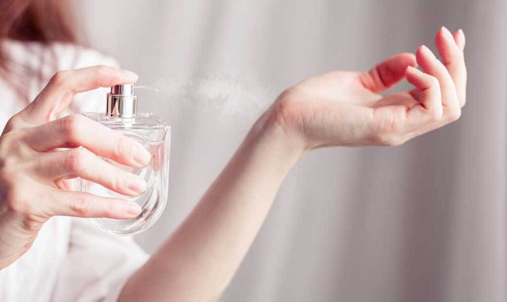 woman spraying perfume on her wrist