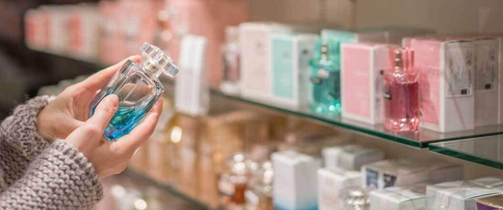 close up of hands holding a bottle of perfume