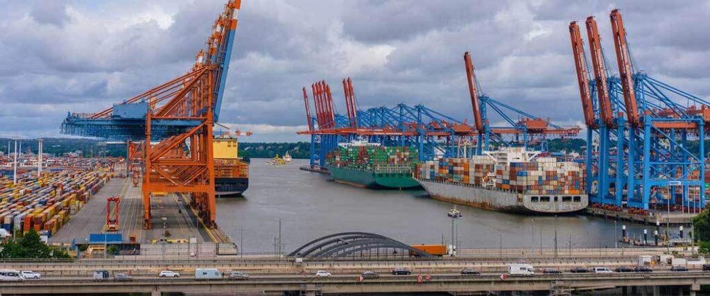 Three cargo ships docked at port under loading cranes.