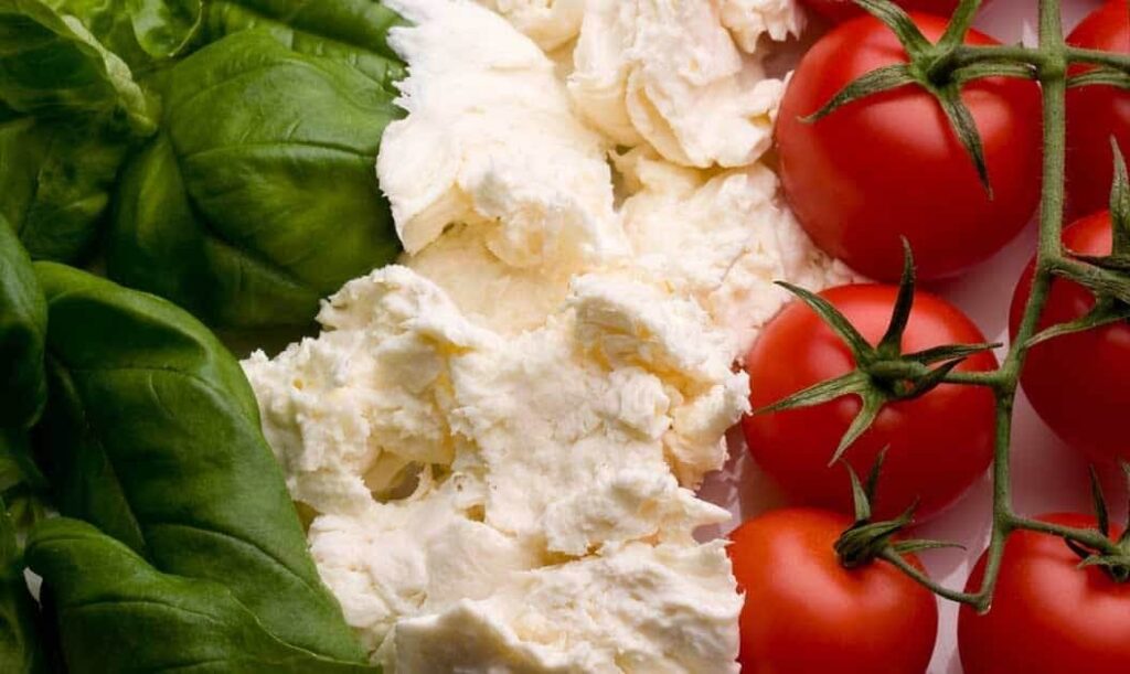 Mozzarella, vine-ripened tomatoes, and basil leaves on a platter.
