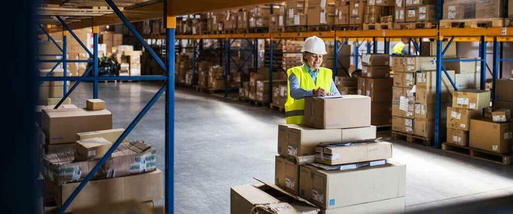 A broker filling out shipping forms in a warehouse.