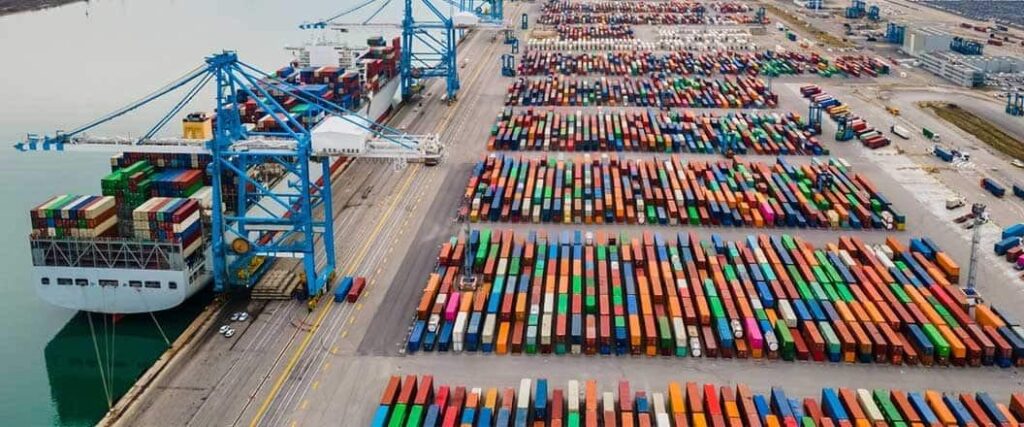 An overhead view of a port with hundreds of shipping containers lined up.