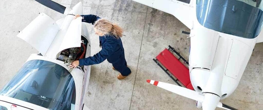 A mechanic inspecting the engine of a small aircraft.