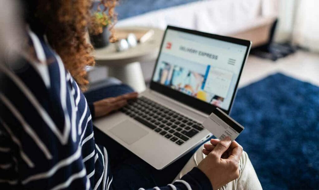 A business owner looking for Alibaba alternatives has a laptop and is holding a credit card in hand.