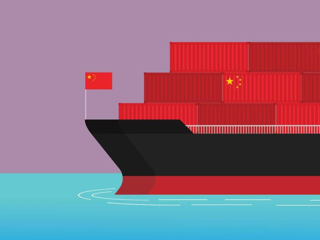 Container ship on the water filled with red shipping containers and with a red flag in the front. One container is stamped with the flag imagery of the People's Republic of China.