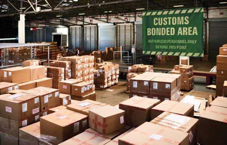 An image depicting the interior of a bonded warehouse, with several packages in the foreground and a sign reading "Customs Bonded Area" in the background.